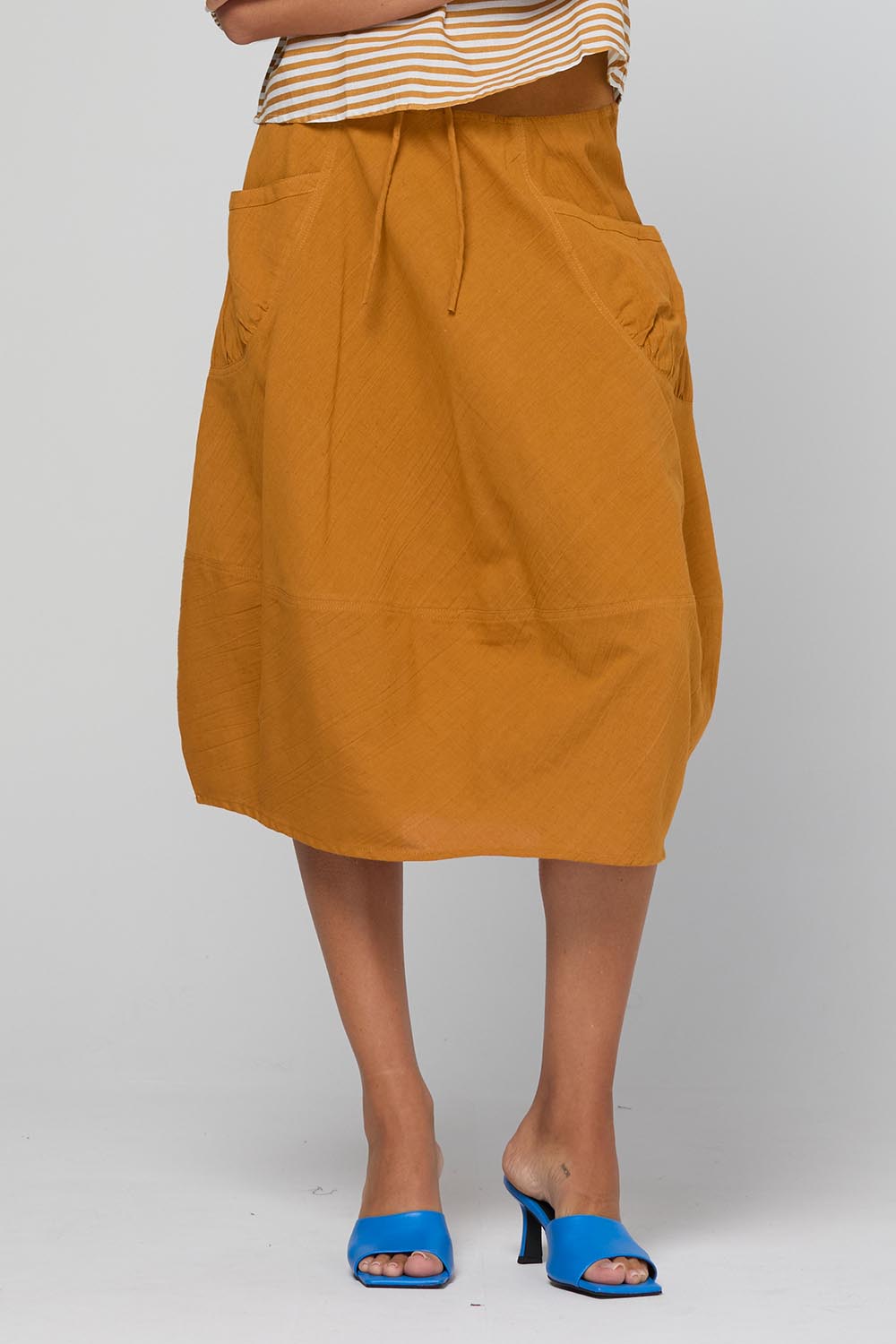 Model Genericm wearing size sample of the Guru Skirt – Turmeric in colour Turmeric, in a cropped view