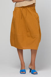 Model Genericm wearing size sample of the Guru Skirt – Turmeric in colour Turmeric, in a cropped view