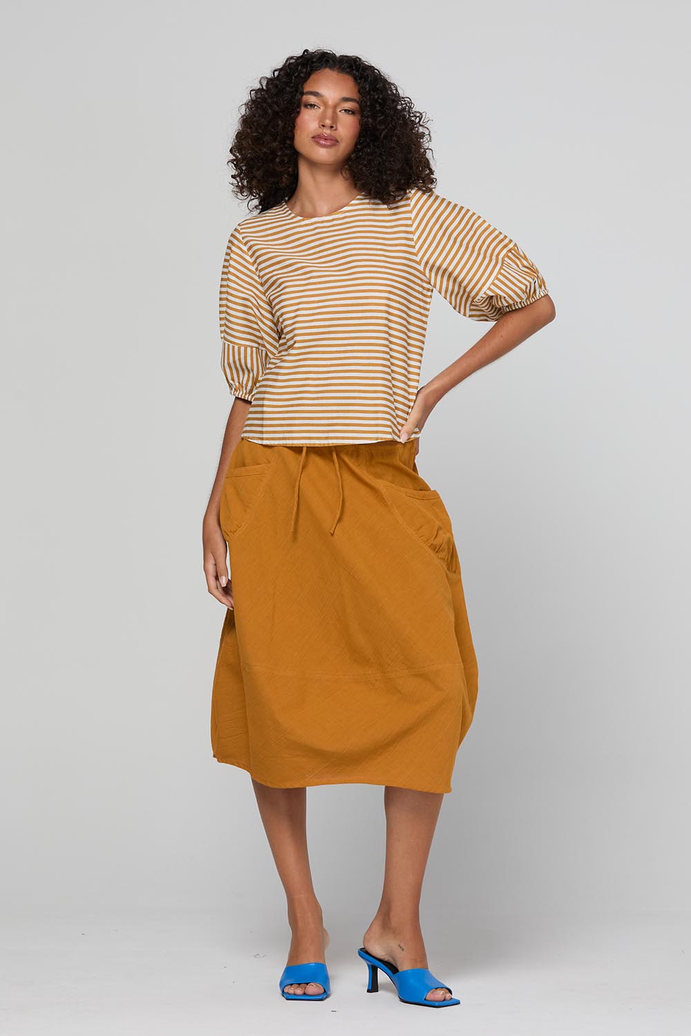 Model Genericm wearing size sample of the Guru Skirt – Turmeric in colour Turmeric, from the front