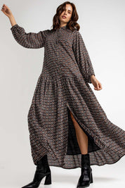 A model wearing the Magari Dress in colour Allora (Black), from the front, showing the whole outfit