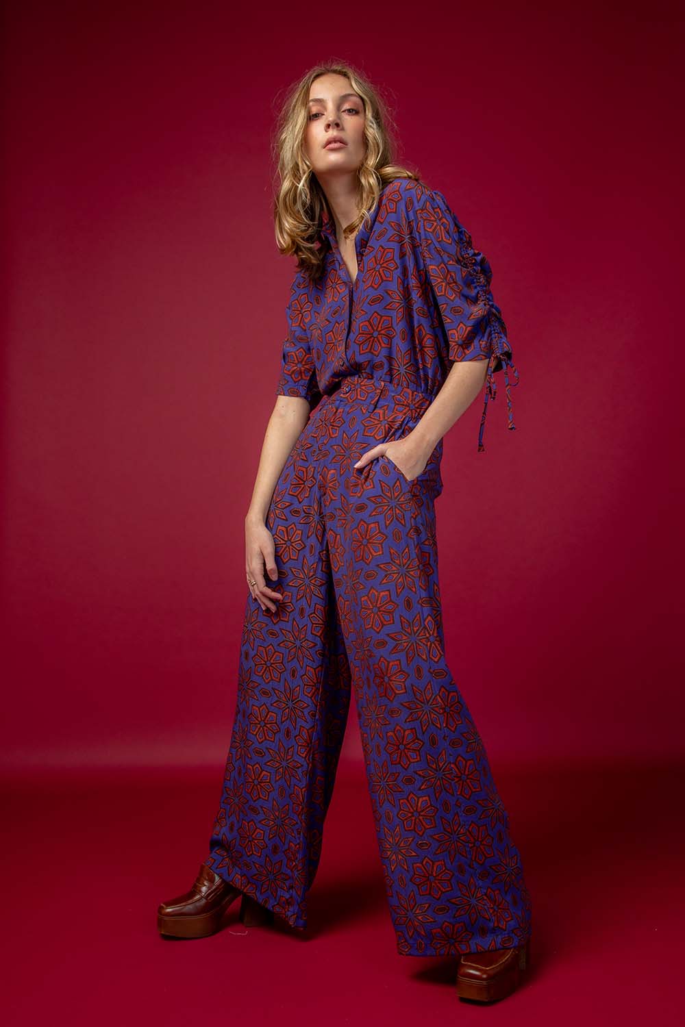 A model wearing the Sara Pant in colour Rio (Purple), from the front, showing the whole outfit