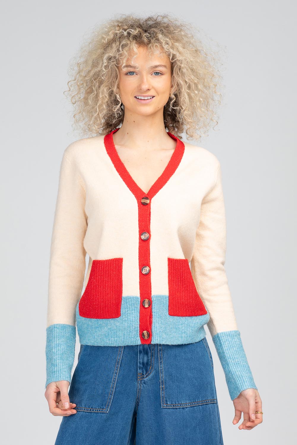 A model wearing the Poet Cardigan in colour Cream, from the front, cropped image