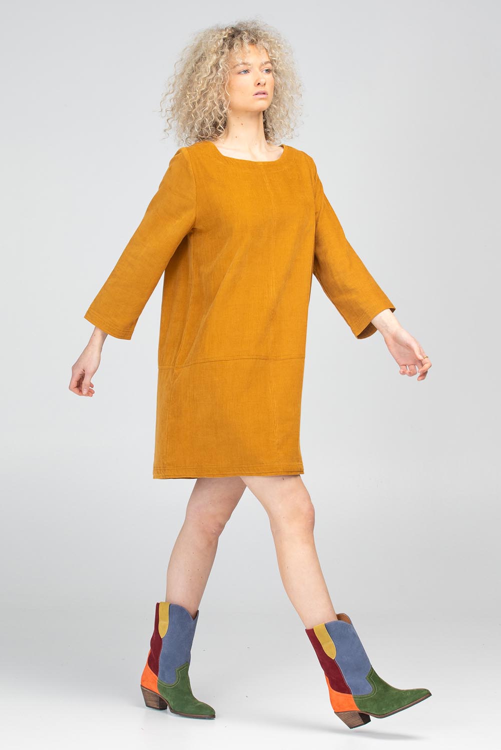 A model wearing the Eva Cotton Cord Dress in colour Marigold, from the front, showing the whole outfit