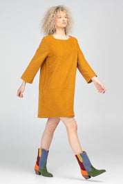 A model wearing the Eva Cotton Cord Dress in colour Marigold, from the front, showing the whole outfit