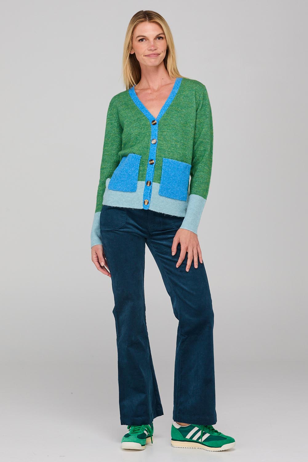 A model wearing the Poet Cardigan in colour Green (Green), from the front, showing the whole outfit