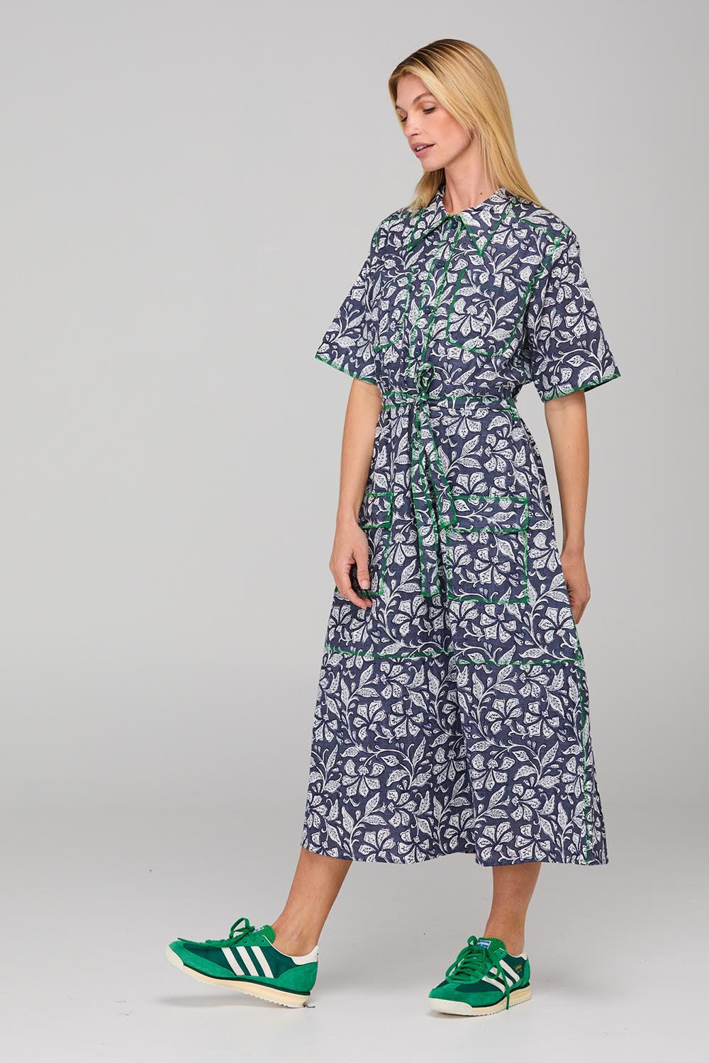 A model wearing the Rishi Dress in colour Izuminavy (Blue), from the front, showing the whole outfit