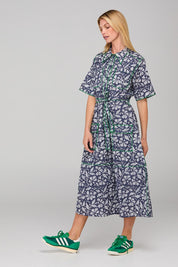 A model wearing the Rishi Dress in colour Izuminavy (Blue), from the front, showing the whole outfit
