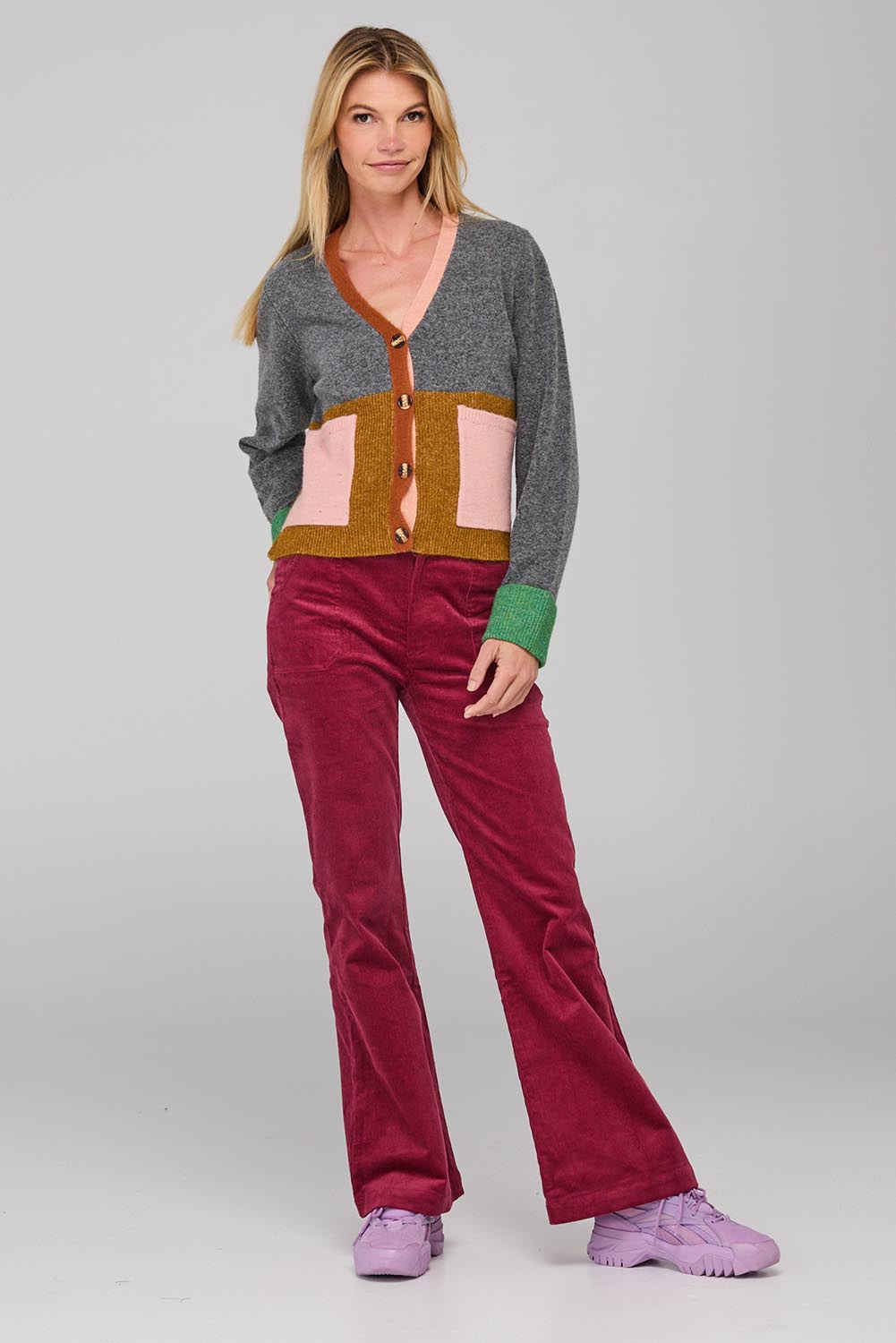 A model wearing the Dharma Pant in colour Cranberry (Red), from the front, showing the whole outfit