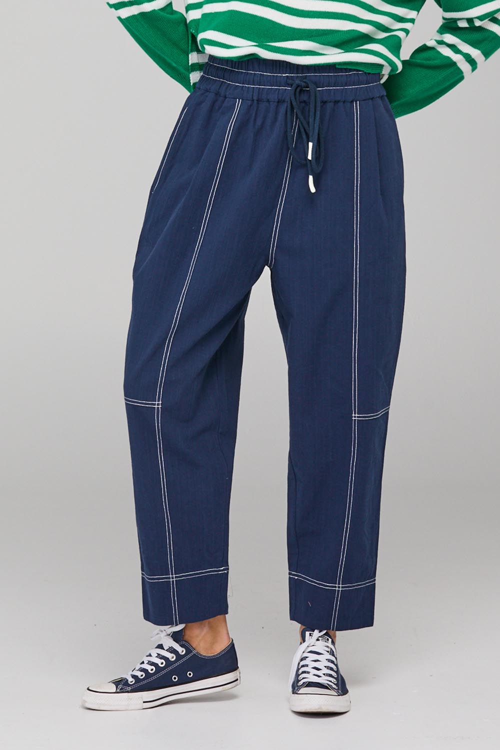 A model wearing the Jonte Pant in colour Navy (Blue), from the front, cropped image