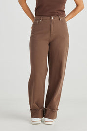 A model wearing the Leroy Pant in colour Chocolate, from the front, cropped image