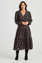 A model wearing the Zion Dress in colour Stonespot (Black), from the front, showing the whole outfit