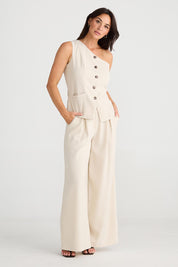 A model wearing the Rozalia Asymmetric Top in colour Oyster, from the front, showing the whole outfit