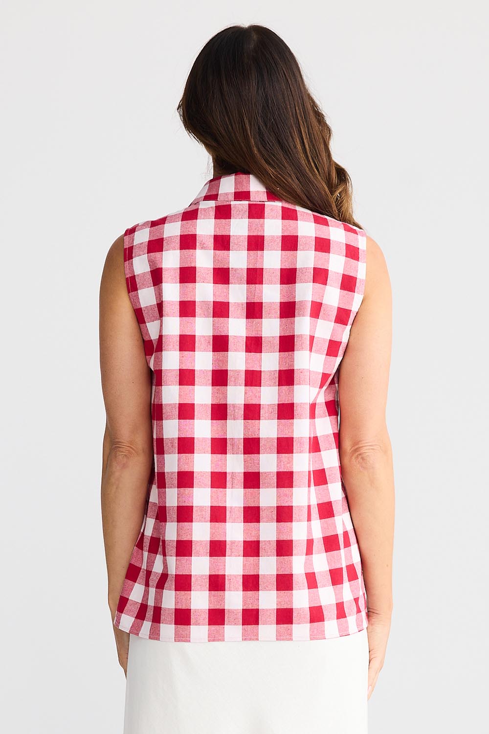 A model wearing the Poppy Sleeveless Cotton Shirt in colour Redgingham (Red), from the back