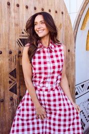 A model wearing the Poppy Sleeveless Cotton Shirt in colour Redgingham (Red), from the front, showing the whole outfit