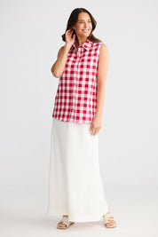 A model wearing the Poppy Sleeveless Cotton Shirt in colour Redgingham (Red), from the front, showing the whole outfit