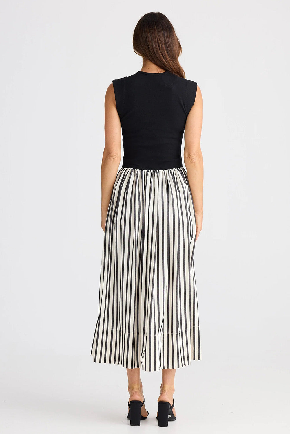 A model wearing the Daphne Dress in colour Blackstrip, from the back