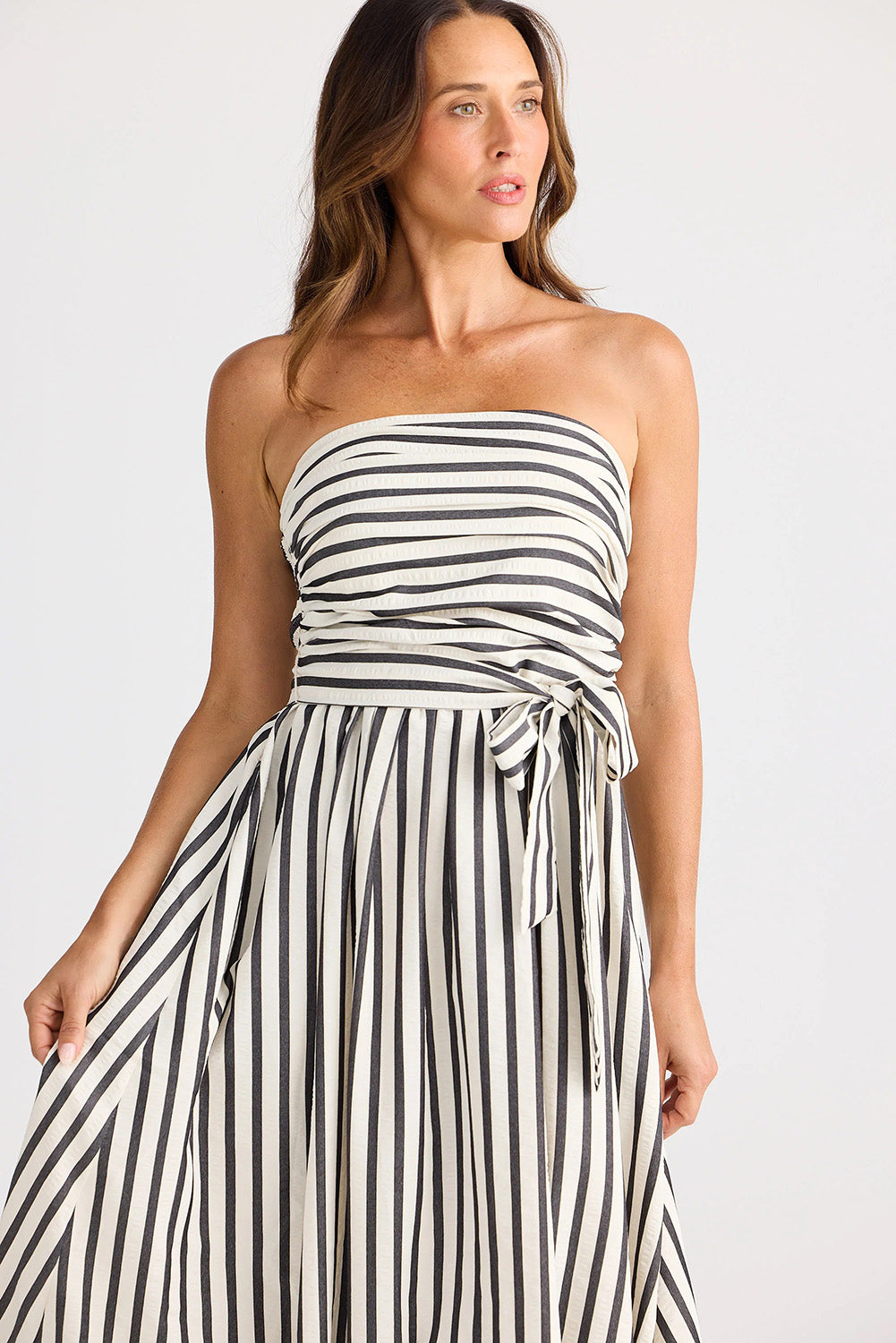 A model wearing the Avalon Dress in colour Blackstrip, from the front, cropped image