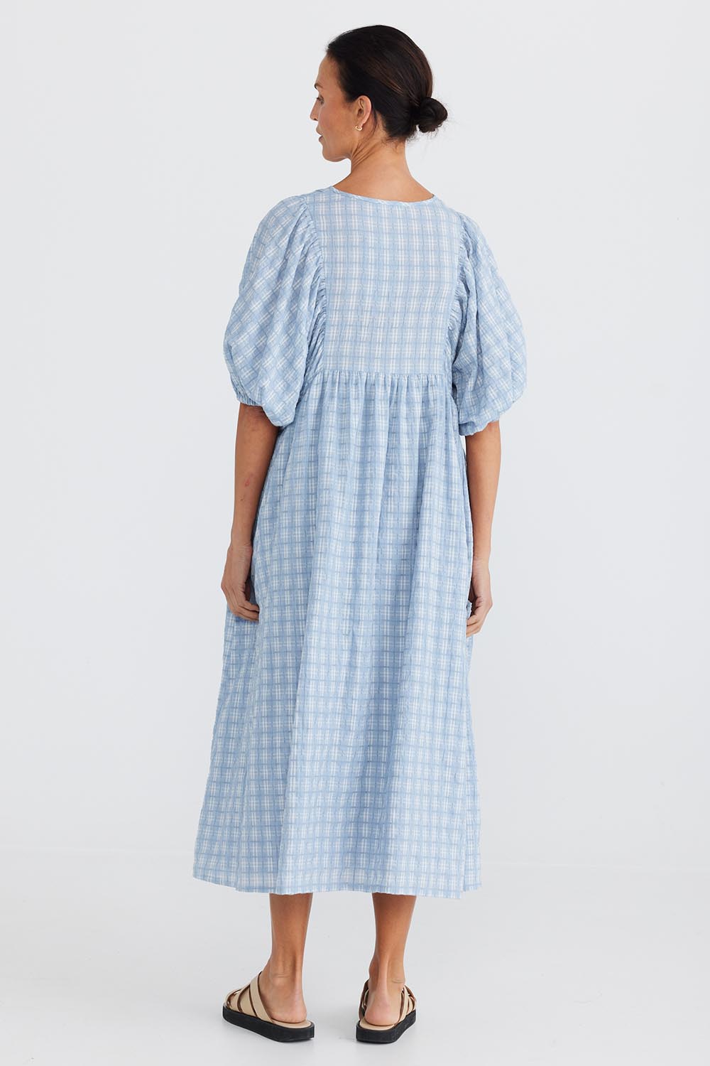 A model wearing the Ciao Bella Dress in colour Bluecheck (Blue), from the back