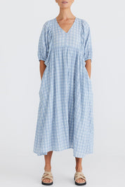 A model wearing the Ciao Bella Dress in colour Bluecheck (Blue), from the front, cropped image