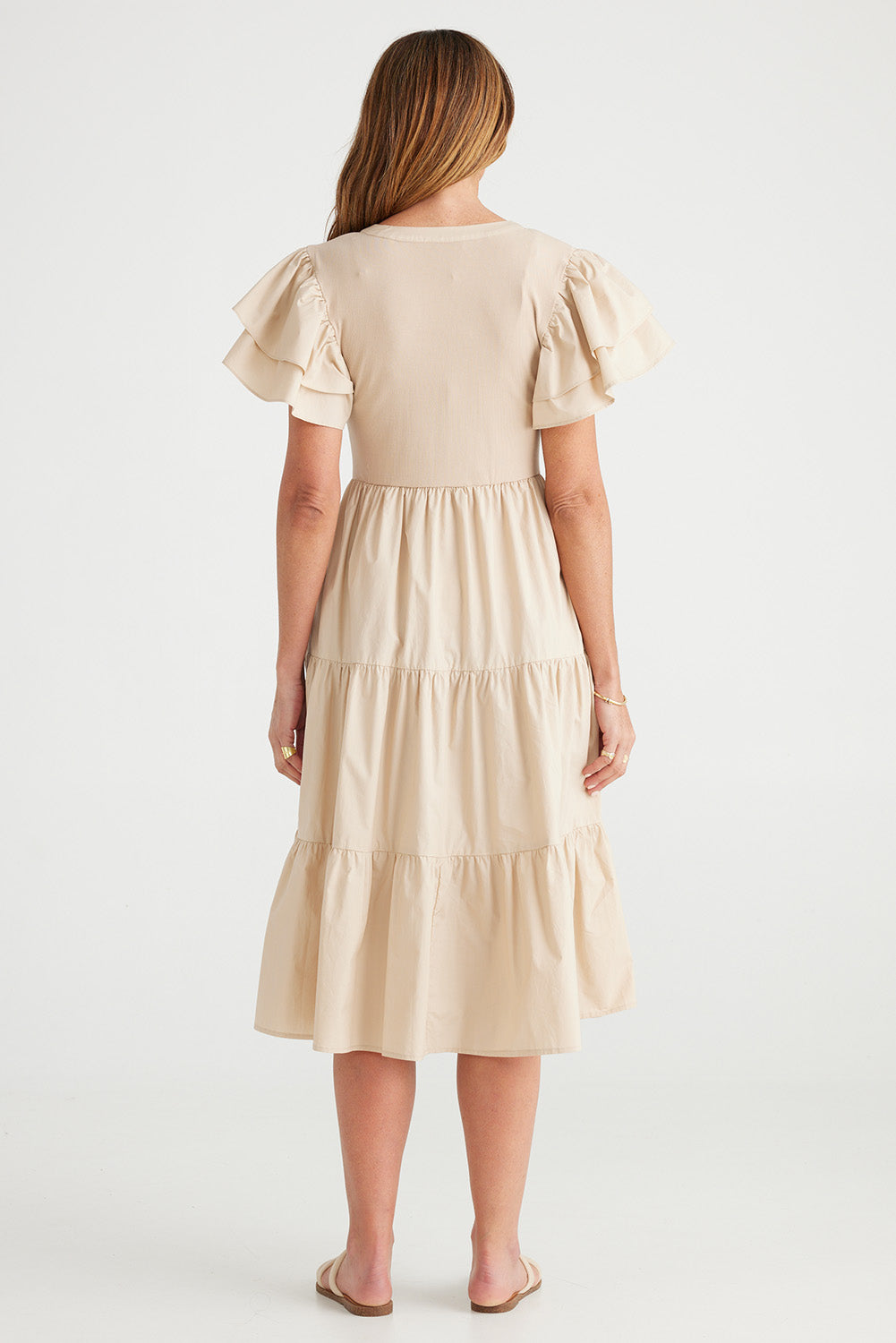 A model wearing the Bella Dress in colour Latte, from the back