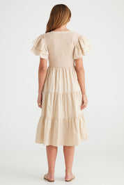A model wearing the Bella Dress in colour Latte, from the back
