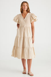 A model wearing the Bella Dress in colour Latte, from the front, showing the whole outfit