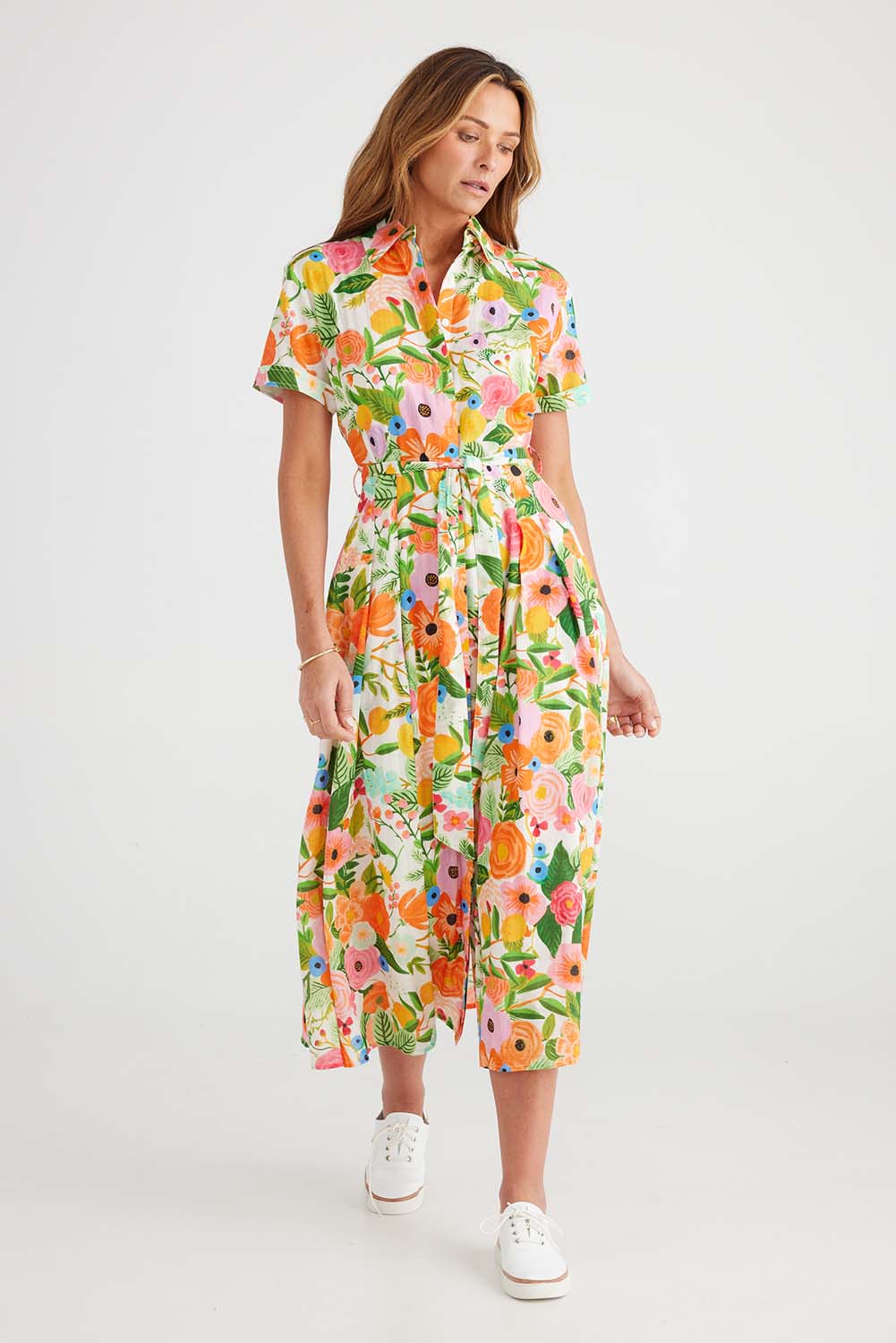 A model wearing the Rosselini Dress in colour Blossom (Green), from the front, showing the whole outfit