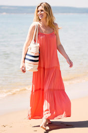 A model wearing the Amara Maxi Dress in colour Coral (Pink), from the front, showing the whole outfit