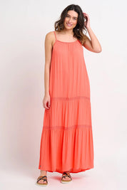 A model wearing the Amara Maxi Dress in colour Coral (Pink), from the front, showing the whole outfit