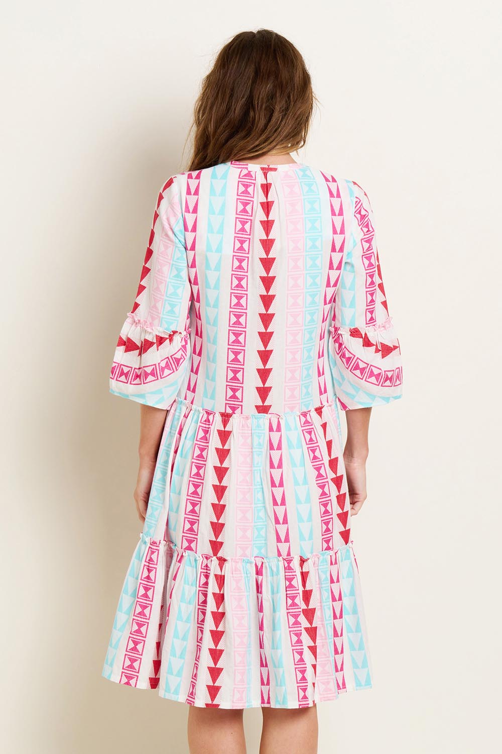 A model wearing the Nessa Dress in colour Multi (Pink), from the back
