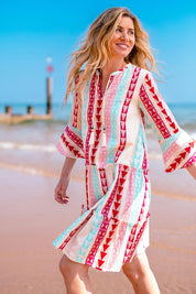A model wearing the Nessa Dress in colour Multi (Pink), from the front, showing the whole outfit