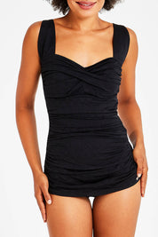 Model Olivia wearing size 10 of the Classique Retro Skirted One Piece in colour Black (Black), from the front, cropped image