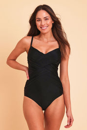 Model Madeline wearing size 10 of the Criss Cross One Piece in colour Black (Black), from the front, showing the whole outfit