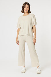 A model wearing the Lounge Pant in colour Natural, from the front, showing the whole outfit