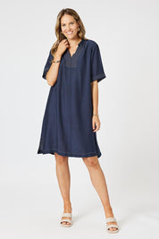A model wearing the Top Stitch Dress in colour Navy (Blue), from the front, showing the whole outfit