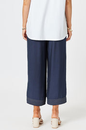 A model wearing the Top Stitch Pant in colour Navy (Blue), from the back