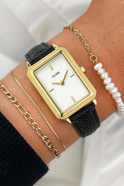 A model wearing the Fluette Black Leather Watch in colour Blackgold (Black), from the front, cropped image
