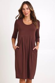 Model Madelinec wearing size 10 of the Box Pleat Dress – Choc in colour Choc, from the front