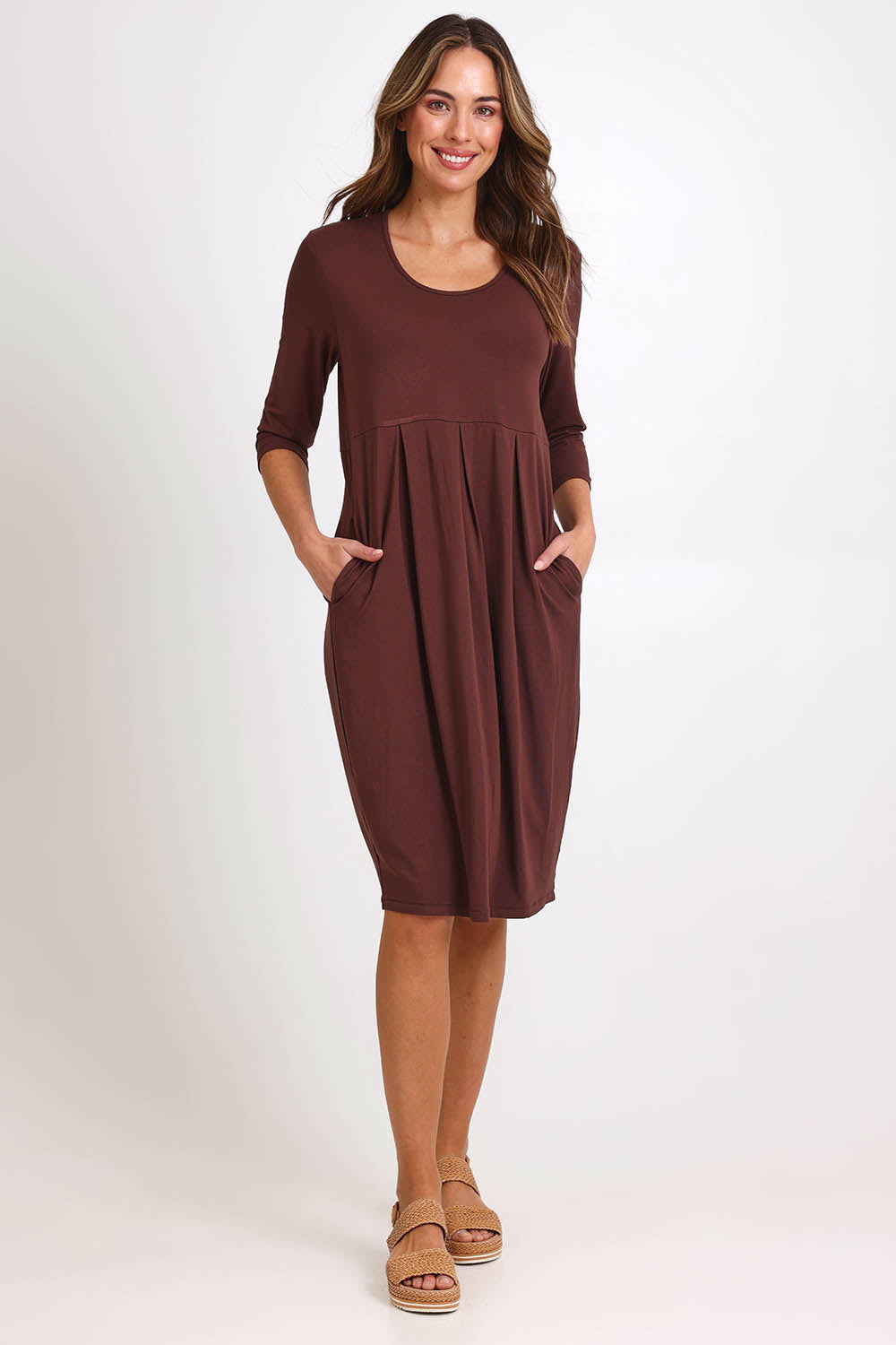 Model Madelinec wearing size 10 of the Box Pleat Dress – Choc in colour Choc, from the front