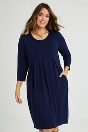 Model Laura wearing size 14 of the Box Pleat Dress in colour Navy (Blue), from the front, cropped image