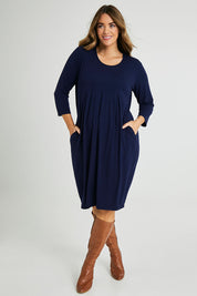 Model Laura wearing size 14 of the Box Pleat Dress in colour Navy (Blue), from the front, showing the whole outfit