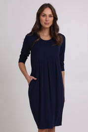 Model Madeline wearing size 10 of the Box Pleat Dress in colour Navy (Blue), from the front, cropped image