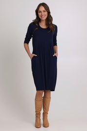 Model Madeline wearing size 10 of the Box Pleat Dress in colour Navy (Blue), from the front, showing the whole outfit