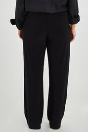 Model Monique wearing size 14 of the Classic Travel Pant in colour Black (Black), from the back