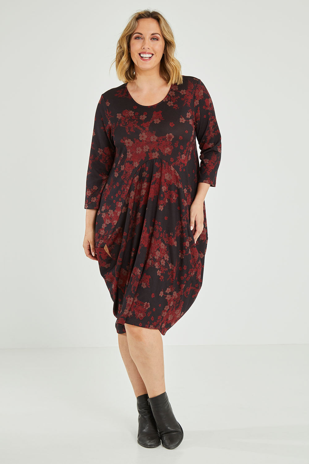 Model Jess wearing size 14 of the Bounce Dress in colour Paperred (Green), from the front, showing the whole outfit