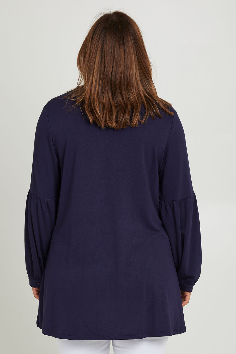 Model Monique wearing size 10 of the Hi Lo Knit Tunic in colour Navy (Blue), from the back