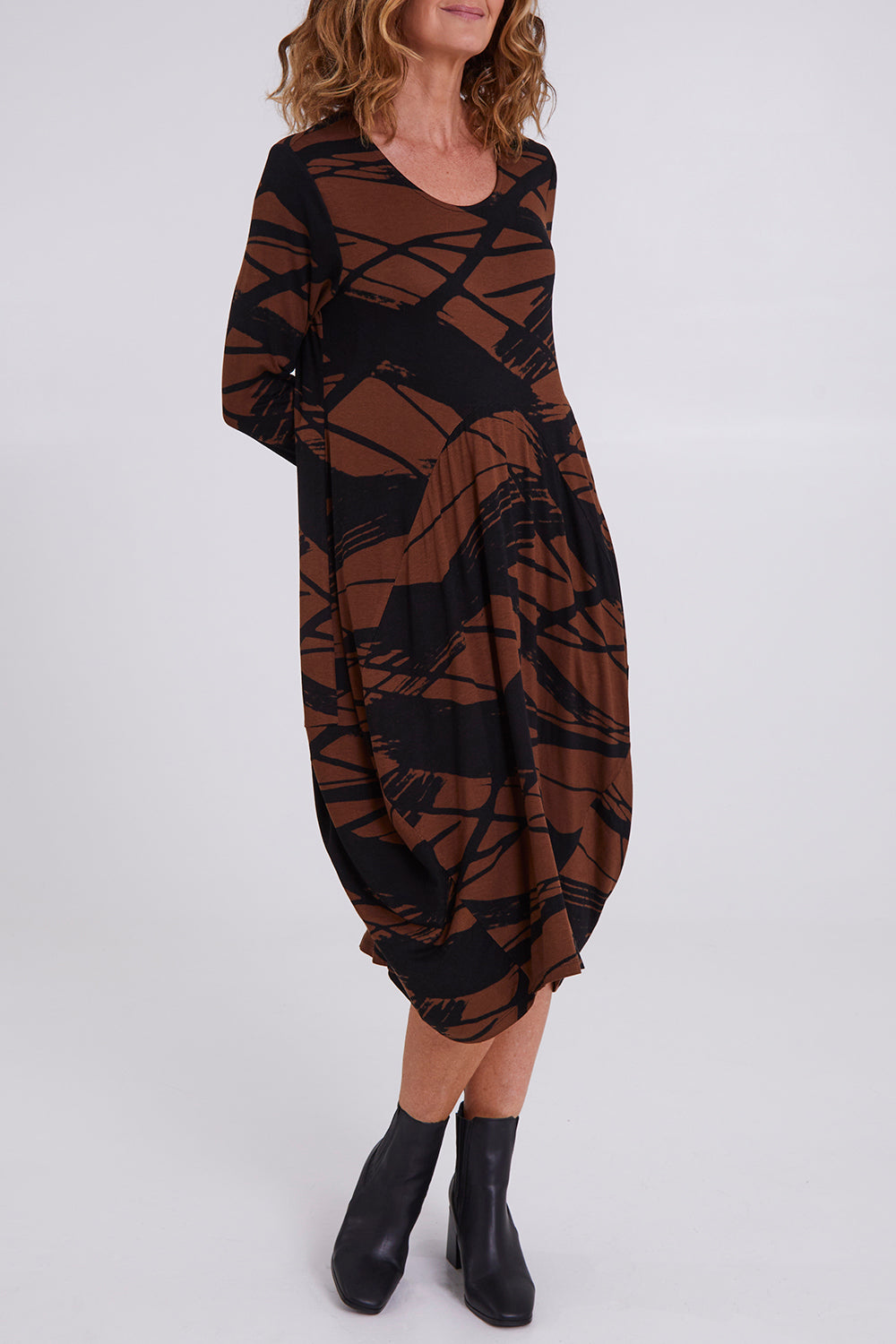 Model Emma wearing size 10 of the Bounce Dress in colour Mocha, from the front, cropped image