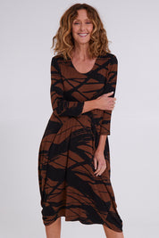 Model Emma wearing size 10 of the Bounce Dress in colour Mocha, from the front, cropped image