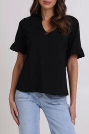 Model Madeline wearing size 10 of the Ruffle Tee Top in colour Black (Black), from the front, cropped image