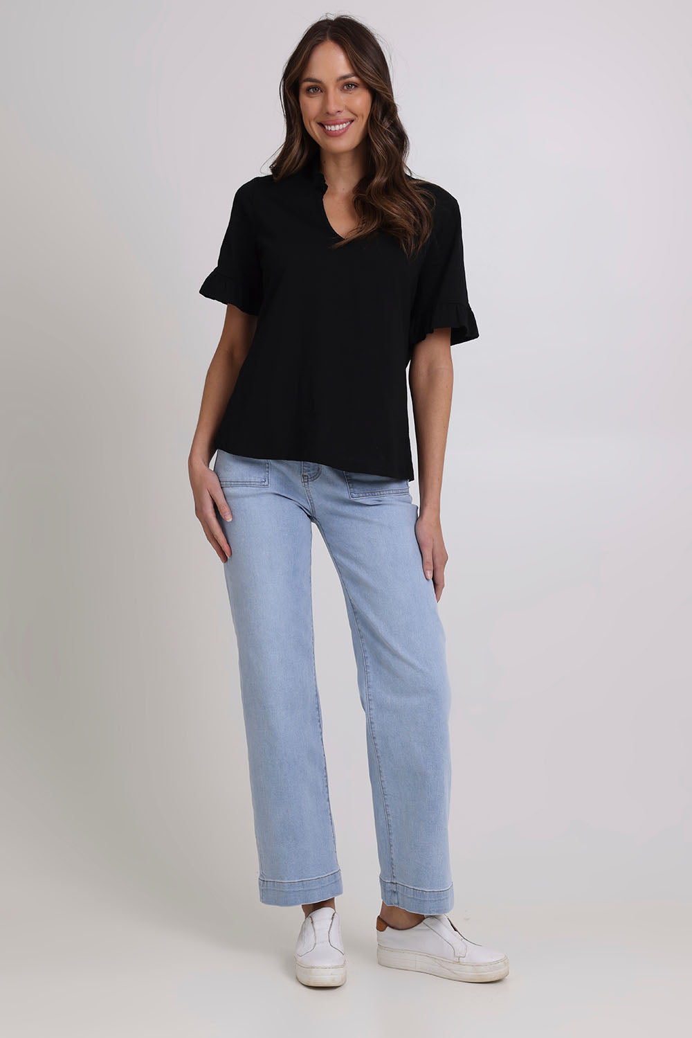 Model Madeline wearing size 10 of the Ruffle Tee Top in colour Black (Black), from the front, showing the whole outfit
